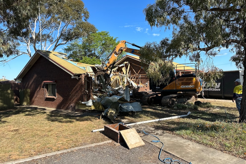 A building being demolished by machinery.