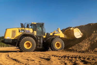 Komatsu WA475-10 wheel loader with bucket digging into dirt pile