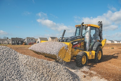 john deere 320 backhoe front loader bucket filled with gravel by gravel pile