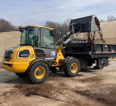 Volvo L25 Electric compact wheel loader dumping dirt into truck bed