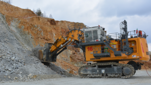 Large orange Liebherr excavator with an extended bucket loading rock rubble at a quarry site on a gravel ground.