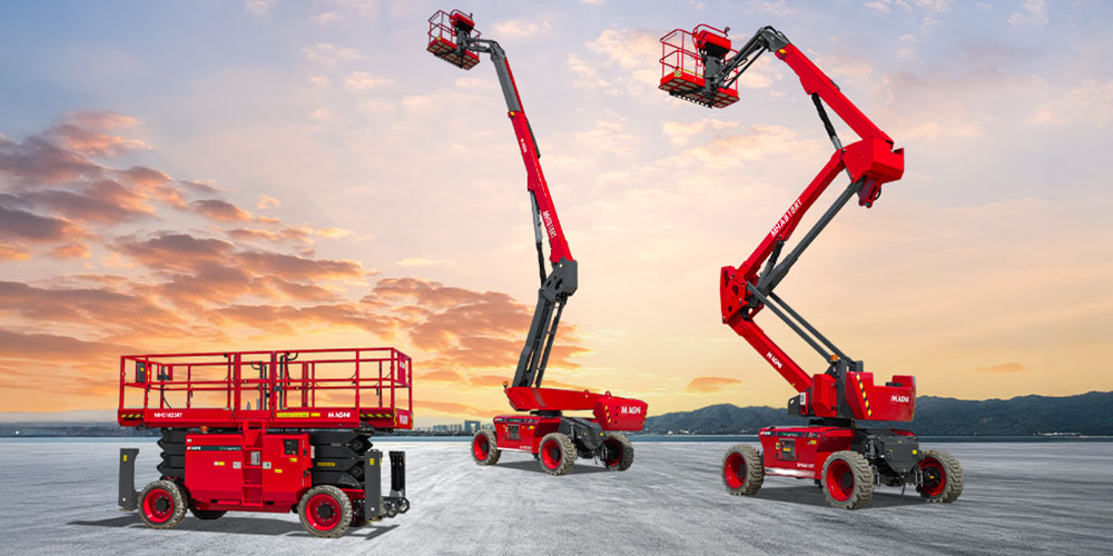 Red telescoping boom lifts on a snowy field at sunset, with three machines ready for work or display.