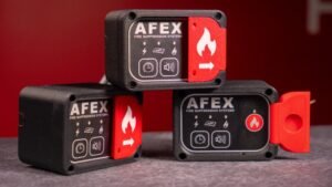 1779407843_63663_en_a9445_65791_afex-compact-panel-fire-supression-unitjpg - Machines Wiki Three AFEX fire suppression control units with red safety toggles on a gray surface.