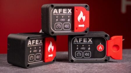 1779407843_63663_en_a9445_65791_afex-compact-panel-fire-supression-unitjpg - Machines Wiki Three AFEX fire suppression control units with red safety toggles on a gray surface.