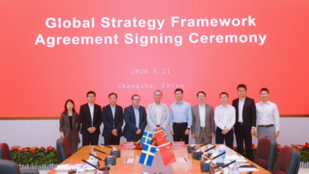 1779826928_63709_en_b0bba_65839_sany-epiroc-sign-agreementpng - Machines Wiki Group of ten professionals standing behind a conference table during a Global Strategy Framework Agreement Signing Ceremony in Changsha, China (red backdrop with date), with Swedish and Chinese flags on the table.