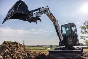 905x0_s3-71325-MNSW-EX-CYCLE-TIMES-1jpg - Machines Wiki Excavator with digging bucket raised over a dirt pile at a construction site under a bright blue sky