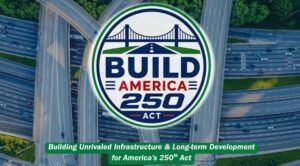 905x0_s3-71395-Screenshot-2026-05-22-at-9_40_08-AMjpg - Machines Wiki Circular 'BUILD AMERICA 250 ACT' logo over a highway interchange seen from above. A green banner below reads, 'Building Unrivaled Infrastructure & Long-term Development for America's 250th Act.'