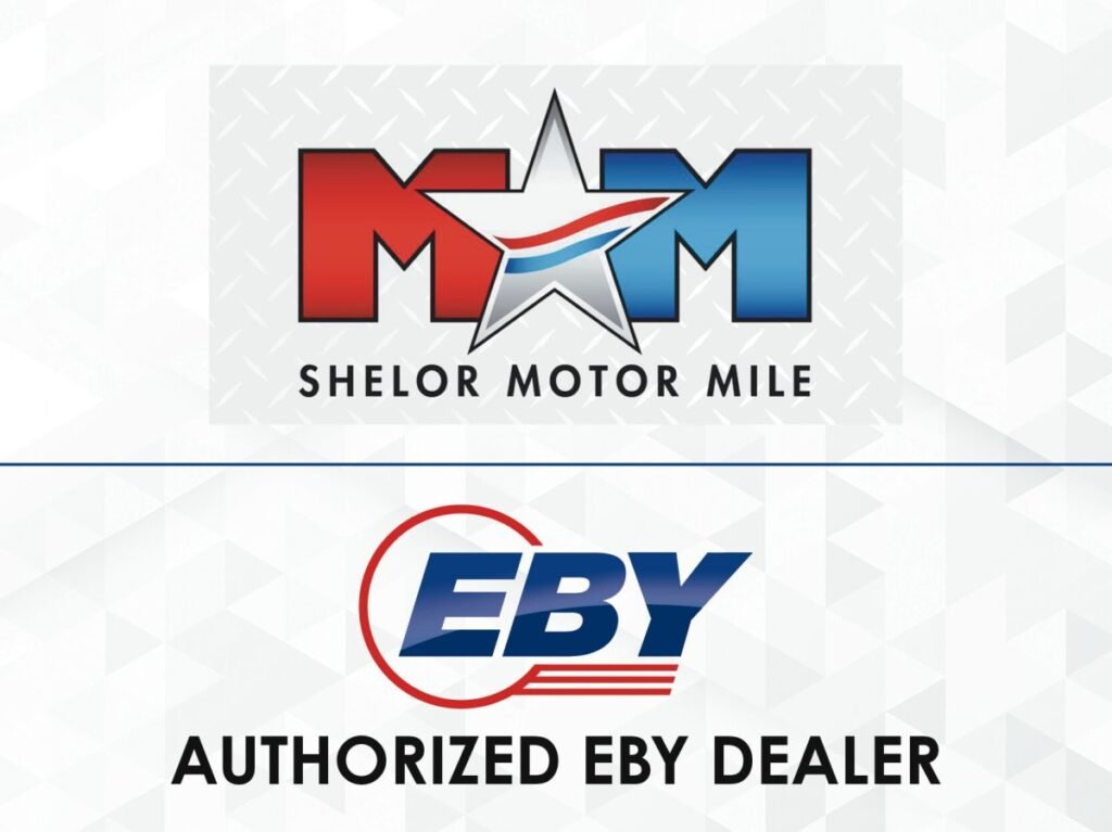 905x0_s3-71404-S-EBY-SHELORjpg - Machines Wiki Shelor Motor Mile logo above an EBY Authorized Dealer banner on a light geometric background.