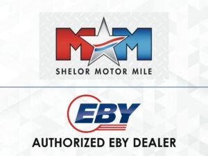 905x0_s3-71404-S-EBY-SHELORjpg - Machines Wiki Shelor Motor Mile logo above an EBY Authorized Dealer banner on a light geometric background.