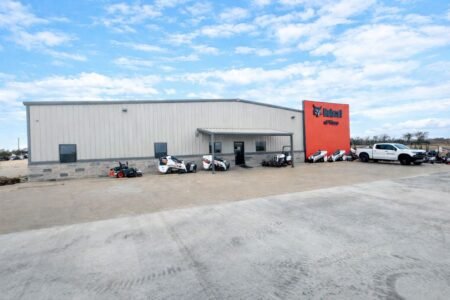 905x0_s3-71432-W-BOBCAT-WACO-1jpg - Machines Wiki Warehouse-style building with a red Bobcat of Waco sign and several Bobcat utility vehicles parked outside