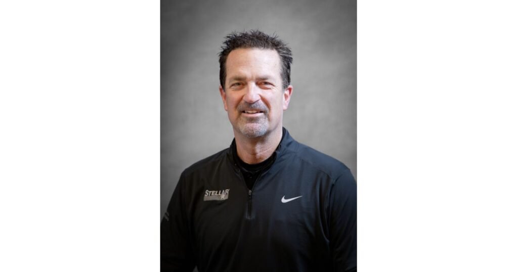 905x0_s3-71436-Chris-Rycroftjpg - Machines Wiki Portrait of a middle-aged man with short dark hair and a goatee, wearing a black athletic jacket with Stellar and Nike logos, posed against a gray backdrop for a staff profile.
