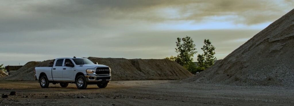 White pickup truck parked near large piles of gravel at a quarry or gravel pit