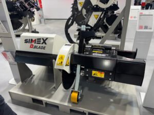 Simex Expands Road Construction Range with D-BLADE 200 Floor Saw Industrial SIMEX Blade machine on display at a trade show, showing warning stickers, yellow roller and dark metal framework used for cutting or shredding material