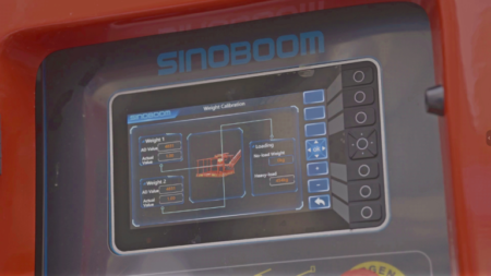 1780512928_63745_en_7c950_65878_sinoboom-smarthub-screenpng - Machines Wiki Close-up of a blue touchscreen labeled 'Weight Calibration' on a red Sinoboom machine, showing load weight readouts and a small orange pallet graphic.
