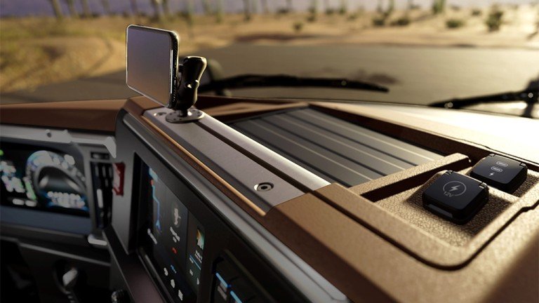 1781032037_63785_en_41791_65920_mack-trucks-granite-cab-dashjpg - Machines Wiki Dashboard interior with a smartphone mounted on a hold‑and‑go mount for navigation, desert road visible outside.