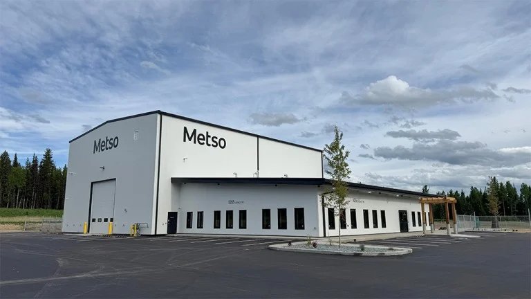 1781921514_63842_en_964b0_65987_metso-prince-george-bc-facilityjpg - Machines Wiki Large white industrial building with the Metso logo, set in an empty parking area under a partly cloudy sky.