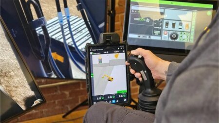 Operator uses a joystick while viewing a tablet crane-simulation app for training in a control rig.