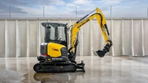 New Holland unveils its most extensive mini excavator lineup yet New Holland E38 compact excavator on wet concrete, yellow arm raised with bucket over the ground.