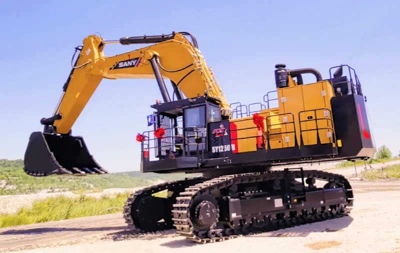 SANYjpg - Machines Wiki Large yellow hydraulic excavator on tracks with extended arm and bucket parked on a dirt lot.