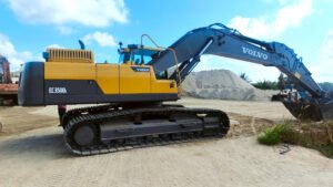 Volvo-CE-delivers-first-machines-under-Approved-Used-Equipment-Program-in-Region-Asia_02jpg - Machines Wiki Yellow Volvo EC350D L excavator on tracks at a dirt construction site with a large pile of soil and blue sky behind it