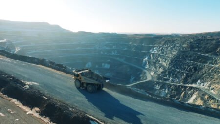epiroc_jpg - Machines Wiki Open-pit mining site with a large dump truck on a winding road along terraced quarry walls at dusk/dawn light