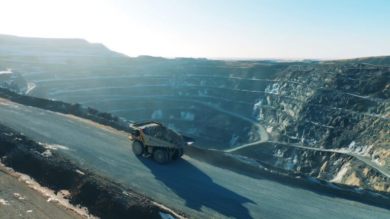 epiroc_jpg - Machines Wiki Open-pit mining site with a large dump truck on a winding road along terraced quarry walls at dusk/dawn light