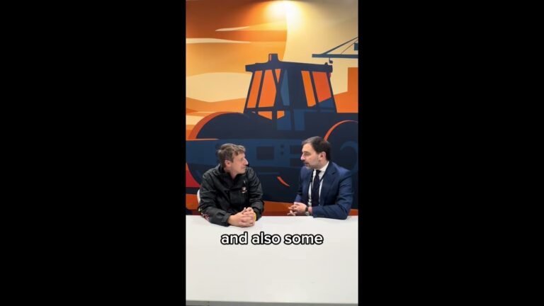 Two men sit at a white table in a studio, conversing in front of a bold orange-and-blue industrial mural; captions read “and also some.”