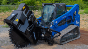 1783624258_63980_en_d2c43_66139_bluediamond-road-sawpng - Machines Wiki Blue compact track loader with a large black mulching head attached on a gravel surface.