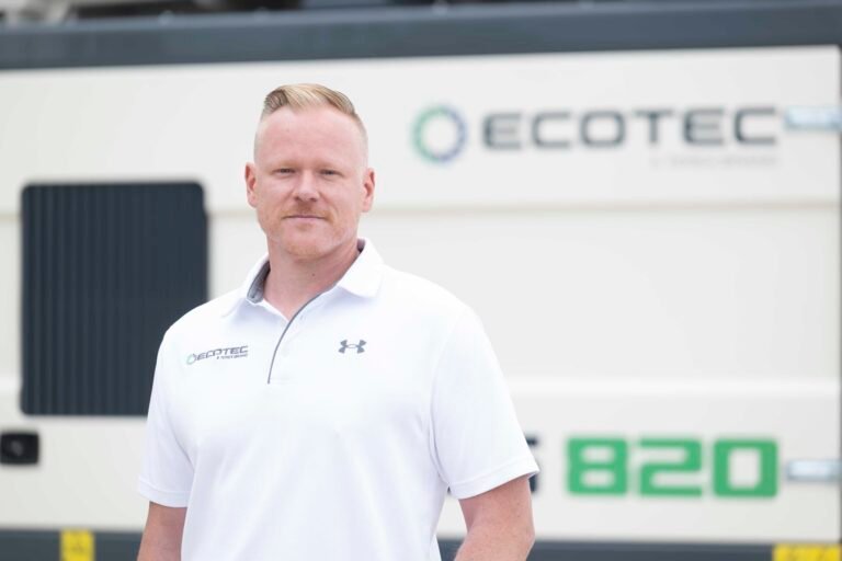 Portrait of a man in a white polo outdoors beside an ECOTEC-branded building.