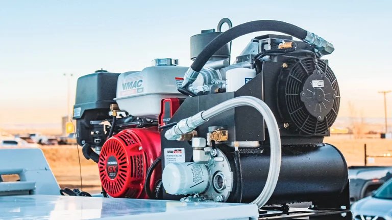 Gas-powered air compressor unit mounted on a vehicle, with a red starter and hoses connecting to the system.”] ,