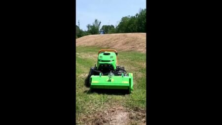 maxresdefault-2jpg - Machines Wiki Green riding lawn mower with a large front mower deck operating on a grassy field.