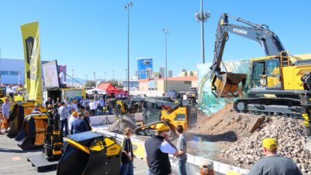 1787000392_63867_en_9985e_66002_conexpo-earthmoving-roundupjpg - Machines Wiki Outdoor construction equipment expo with a large yellow Hyundai excavator on a rocky display and visitors nearby